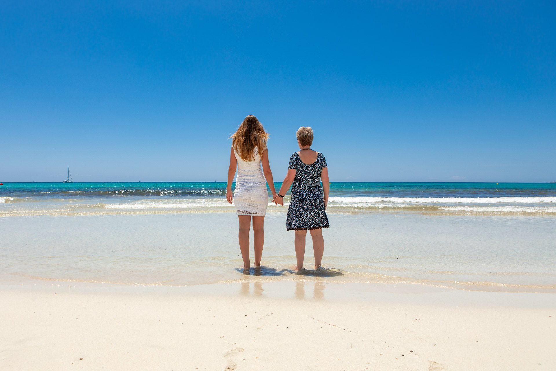 Mutter und Tochter stehen am Es Trenc Strand und schauen aufs offene Meer bei wunder schönem blauen Himmel